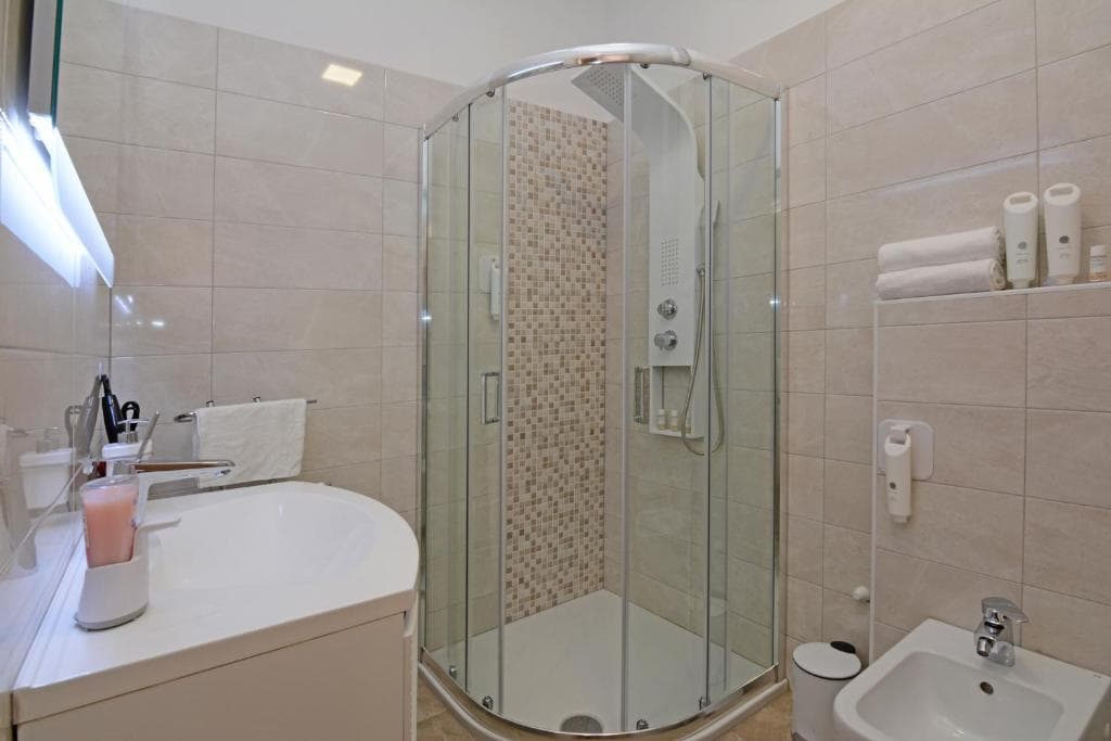 Bathroom with a corner glass shower, a washbasin and a bidet