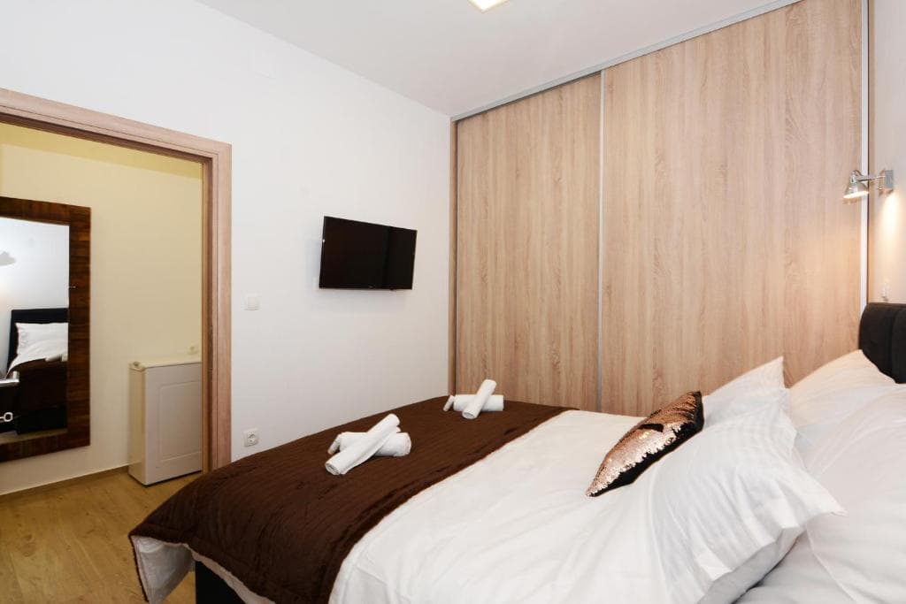 Bedroom with a large double bed, a wall-mounted TV and a wooden sliding wardrobe