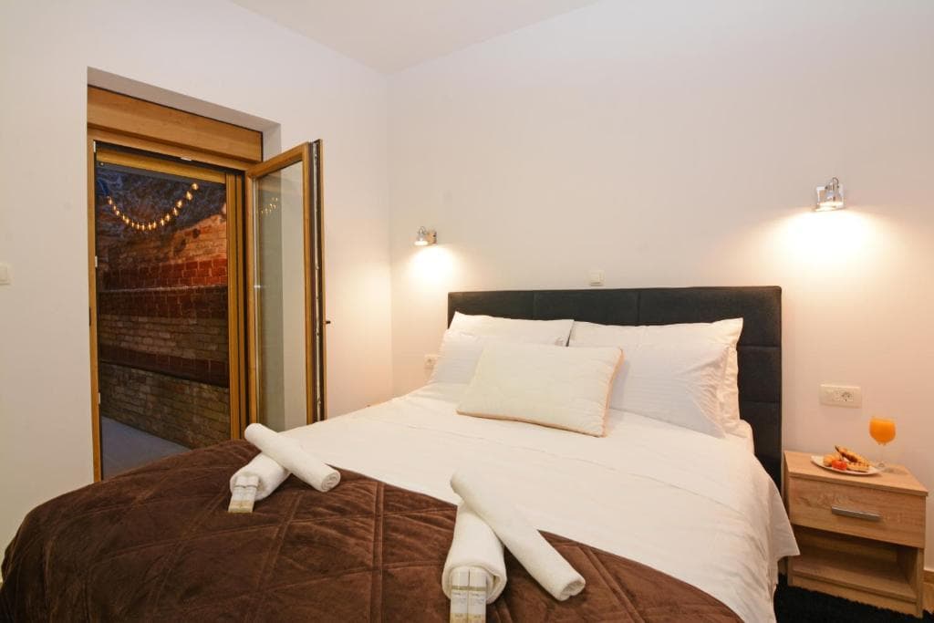 Bedroom with a large double bed and a glazed door to an outdoor area with string lights