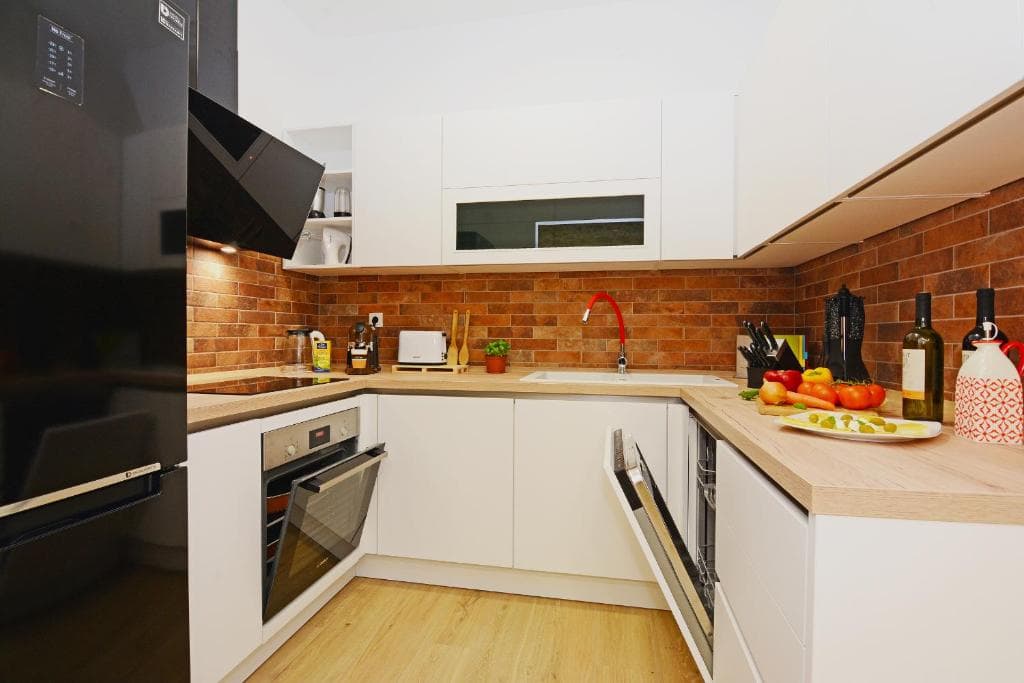 White kitchen with a fridge, oven, hob and a brick-style splashback